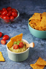 Homemade guacamole with corn chips and cherry tomatoes
