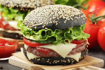 A black burger with vegetables and beef meat