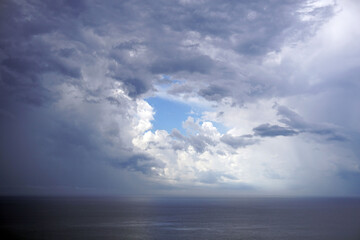mediterranean sea landscape with cloudy sky and a small piece of clear sky in the shape of a circle...