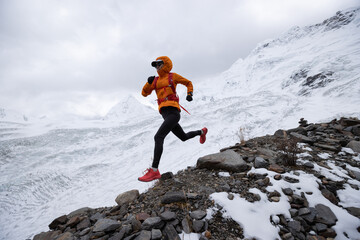 Woman trail runner cross country running down hill from winter snow mountain top