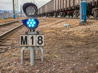 Small railway traffic light with blue-light signal standing near the railway tracks