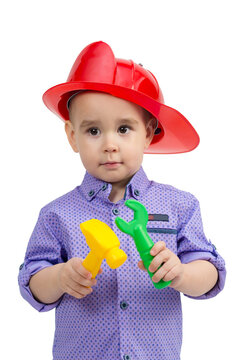Child 3 years old in helmet with construction tools in hands.