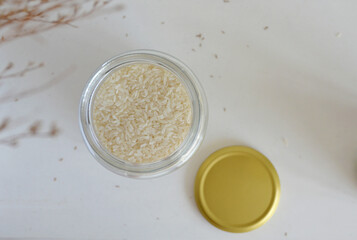 Jar of white Vietnamese jasmine infused rice with brass gold lid. View from top against white background. 