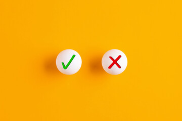 Right versus wrong or voting yes or no. Checkmark and cross icons on table tennis balls on yellow...