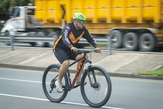 Hombre obeso haciendo deprte montado  en una bicicleta por una carretera