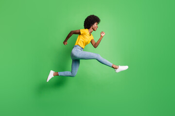 Fototapeta na wymiar Full body profile side photo of curly hair dark skin lady wear yellow t-shirt jeans jump up run copyspace isolated on green color background
