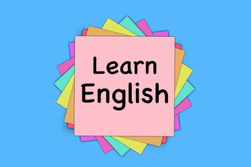 Learn English - lettering on a paper card on a stack of colored stickers on a light blue background.