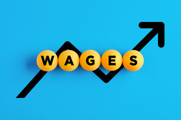 The word wages written on yellow balls with increasing line chart. Wage or salary increase