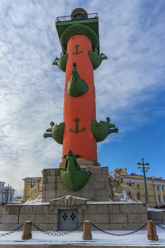 Historical rastral column on Vasilievsky Island in St. Petersburg (Russia) in the spring against the blue sky. The rich decor of the column and the bright red color make it recognizable.