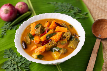 Sambar , Lentil sambar mixed vegetable curry soup for Onam sadhya vishu spicy hot isolated on green banana leaf. popular south Indian food in Kerala Tamil Nadu Sri lanka