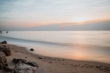 Fototapeta premium long exposure Sea rocks Magnificent sunrise view at sunrise Romantic atmosphere in peaceful morning at sea. Pink horizon with first hot sun rays. 