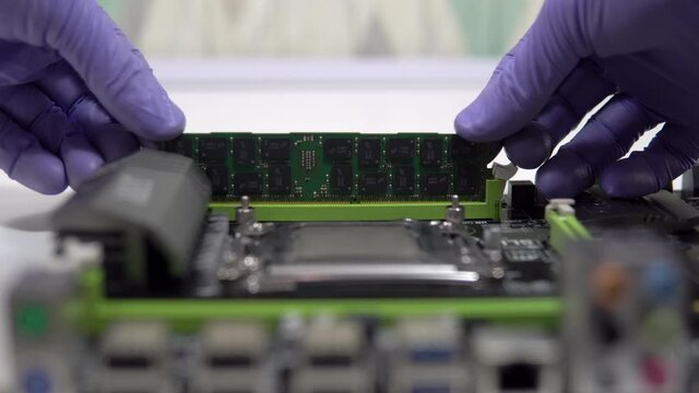 The repair technician inserts a RAM stick into the socket on the motherboard. Maintenance and modernization of a personal computer