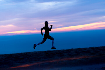 Running man silhouette on sunset sky backdrop