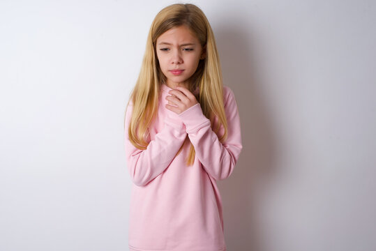 Sad beautiful caucasian little girl wearing pink hoodie over white background feeling upset while spending time at home alone staring at camera with unhappy or regretful look.