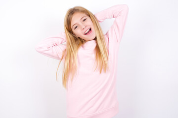 beautiful caucasian little girl wearing pink hoodie over white background relaxing and stretching, arms and hands behind head and neck smiling happy