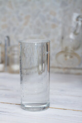 A glass full of clear water sits on the kitchen table. Copy space