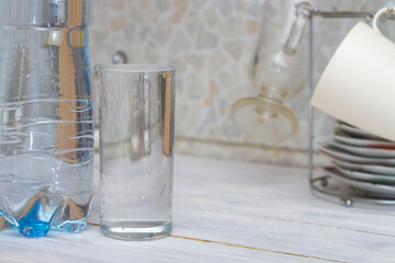 A glass full of clear water sits on the kitchen table. Copy space