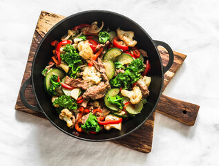 Quick beef stew with zucchini, cauliflower, sweet pepper, kale in a cast-iron pan on a light...