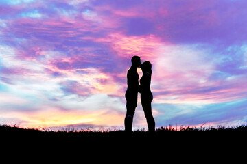 Silhouette couple on grass with sunset background