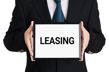 Businessman holds a signboard with the word leasing on isolated white background. Business finance