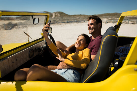 Caucasian couple on a beach buggy by the sea taking selfie