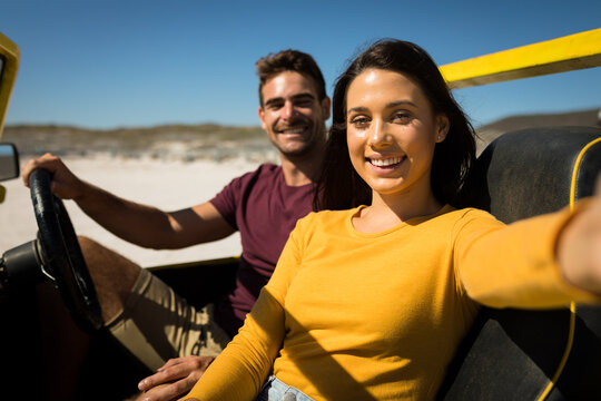 Caucasian couple on a beach buggy by the sea taking selfie