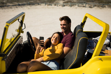 Happy caucasian couple sitting in beach buggy by the sea relaxing