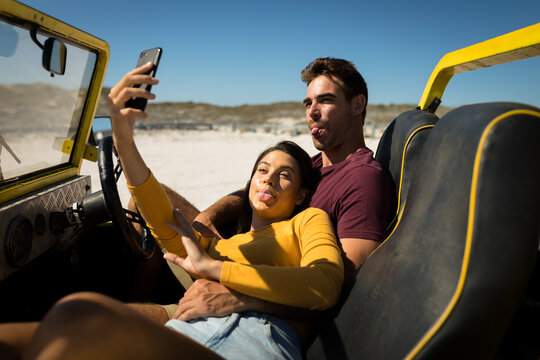 Caucasian couple on a beach buggy by the sea taking selfie - Powered by Adobe