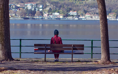 Woman sitting on a bench while looking away to horizon over lake
