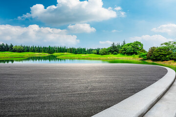 Empty asphalt road and green forest under blue sky.