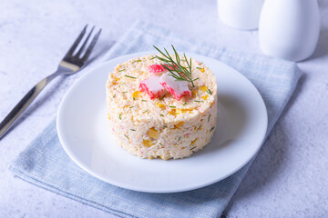 Crab salad with corn and eggs on a white plate. Serving in portions. Traditional Russian salad. Close-up.