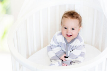 Baby in a white crib. Child in bed.