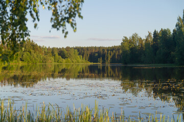 A river or lake with a calm smooth surface on a quiet summer day in the evening
