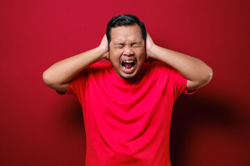 Portrait of young Asian man wearing casual red shirt closing his eyeas and ears dont want or avoiding to hear bad news, stress under mental pressure concept
