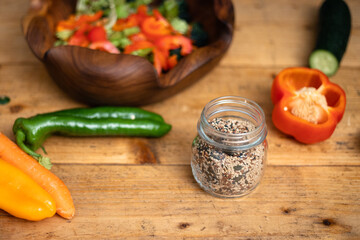 Vegetable salad on wooden table with mix of black and white sesame seeds in a jar 