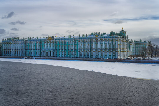 Winter Palace, view from the water area of the Neva (St. Petersburg, Russia) in early spring. An elegant blue palace with luxurious gold trim. The ice on the river has already begun to thaw. Cloudy 