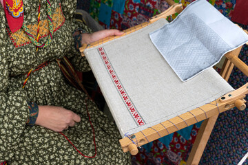 Woman makes cloth on an old loom. Clothing weaving process. Festival of historical reconstruction