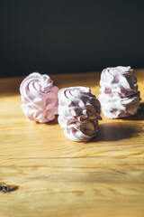 Fresh marshmallows on a wooden background. Zephyr, meringue. The concept of home-cooked food. Minimalism, flat lay, copyspace.