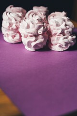 Fresh marshmallows on a purple background. Zephyr, meringue. The concept of home-cooked food, sweets. Minimalism, top view, flat lay, copyspace.