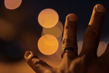 dedos masculinos que portan anillo con un fondo que presenta efecto bokeh