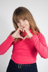 the girl of 10 years shows heart hands a portrait studio