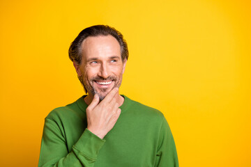 Photo of minded positive man finger chin look empty space wear green sweater isolated vivid yellow color background