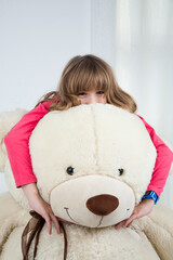 the girl of 10 years poses with a teddy bear smiles portrait studio