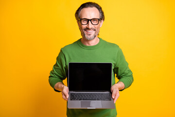 Photo of bearded promoter guy hold netbook screen empty space wear specs green sweater isolated yellow color background