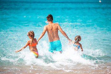 Little girls and happy dad having fun during beach vacation