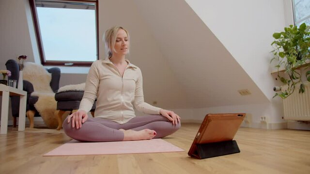 Beautiful middle-aged woman yoga teacher conducting online video lesson from home on her laptop.