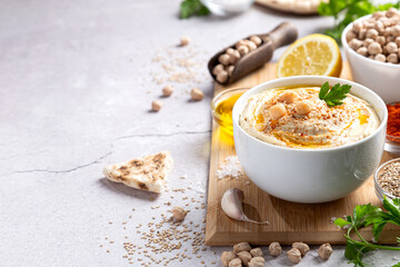 Classic hummus in a bowl with ingredients on light background with copyspace.