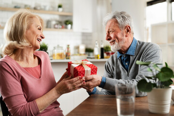 Husband giving a present to his wife. Senior man surprise his beautiful wife