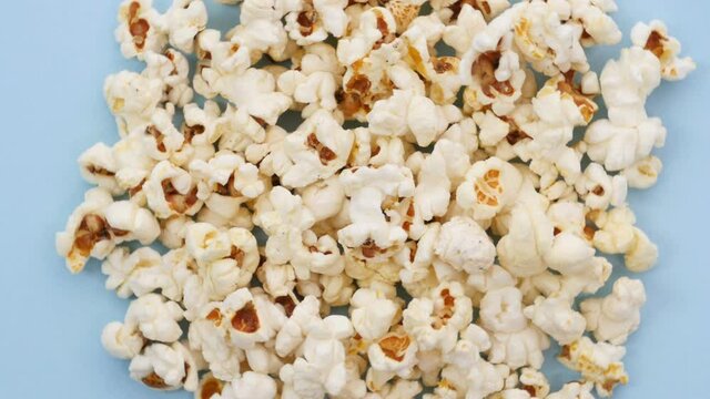 Rotation of pile of popcorn,Heap of popcorn revolving on blue surface, junk food, movie time, going to cinema, hanging out with friends. Close up, 4K Ultra HD.