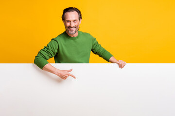 Photo of promoter man hold white placard direct finger empty space wear green sweater isolated...